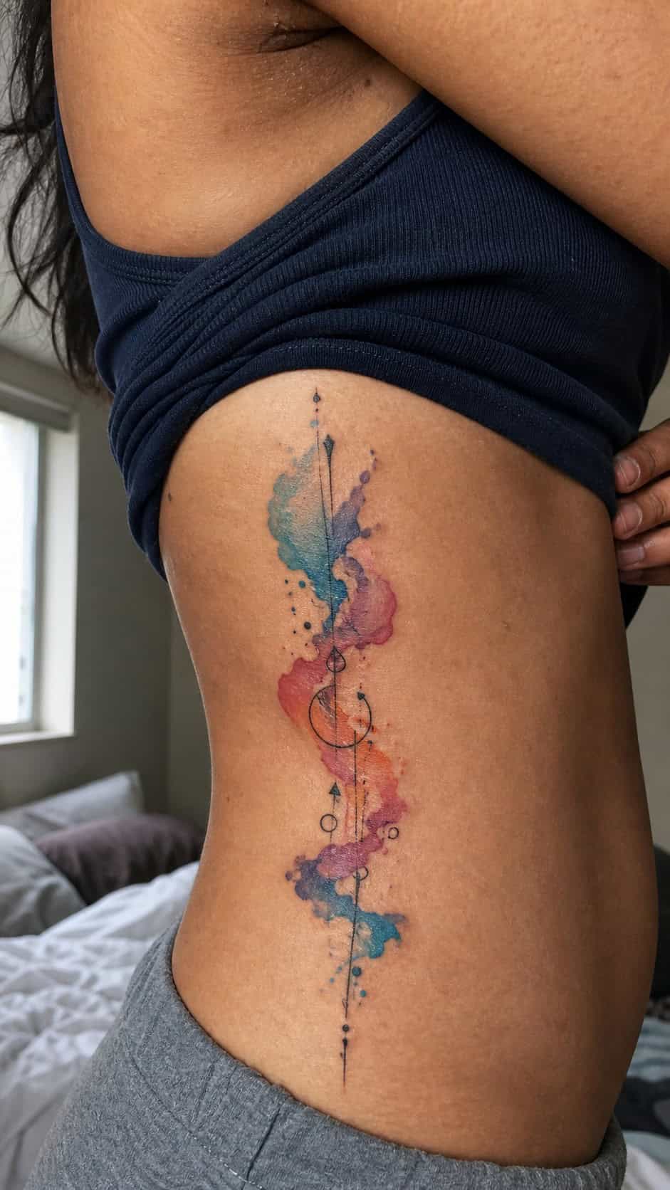 32 Stunning Rib Tattoos for Women 8 Healed abstract watercolor tattoo on a adult woman's side ribs, photographed in a natural slightly elevated close view — study 1