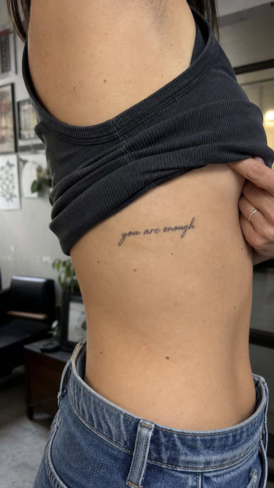 32 Stunning Rib Tattoos for Women 10 Healed script writing tattoo on a adult woman's side ribs, photographed in a natural relaxed documentary crop — study 1