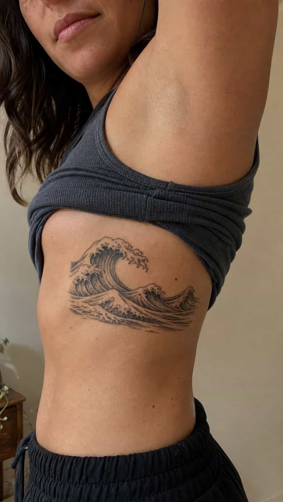 32 Stunning Rib Tattoos for Women 16 Healed ocean waves tattoo on a adult woman's side ribs, photographed in a natural relaxed documentary crop — study 1