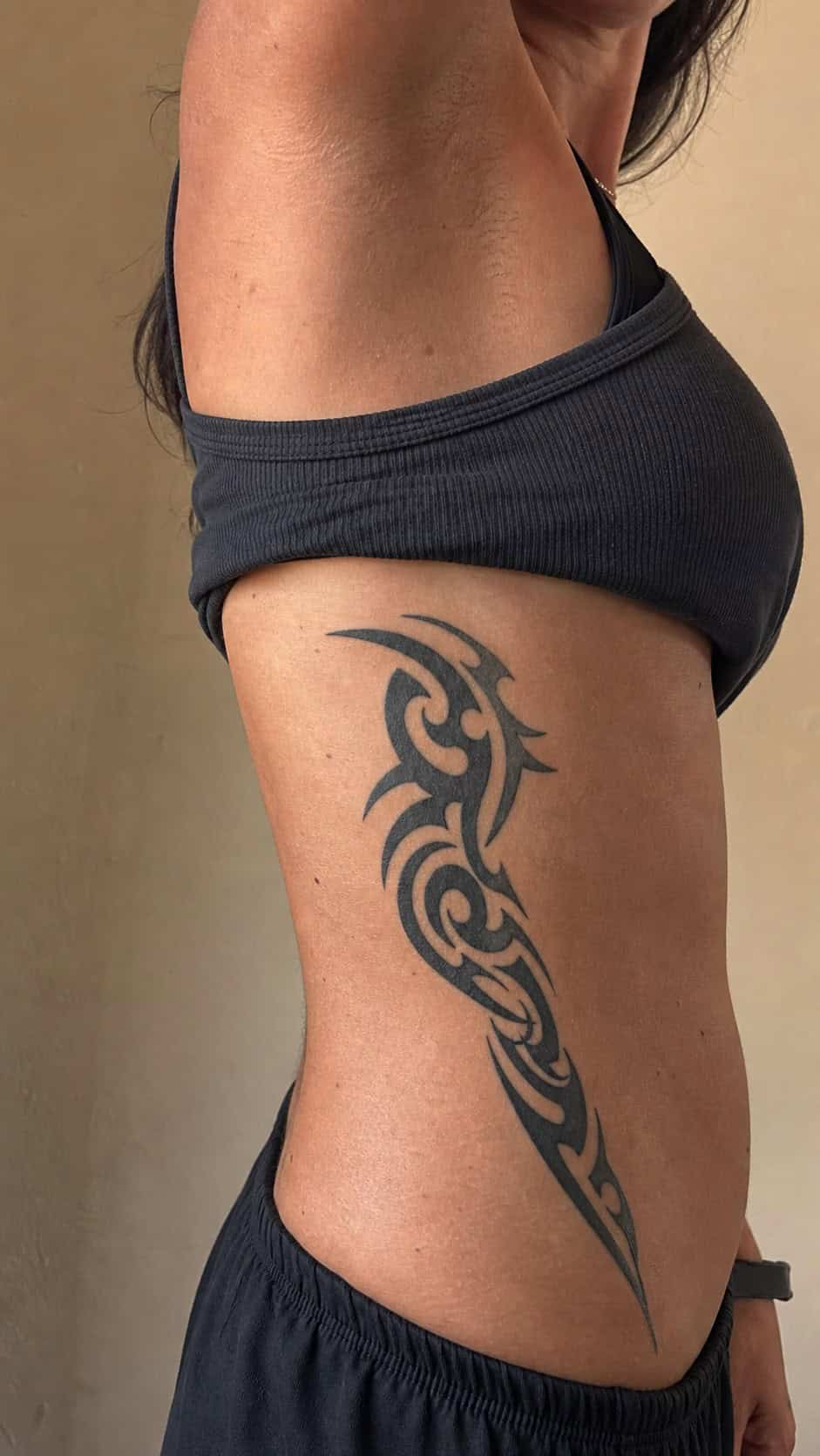 32 Stunning Rib Tattoos for Women 24 Healed tribal designs tattoo on a adult woman's side ribs, photographed in a natural gentle side angle that clearly shows how the ink — study 1