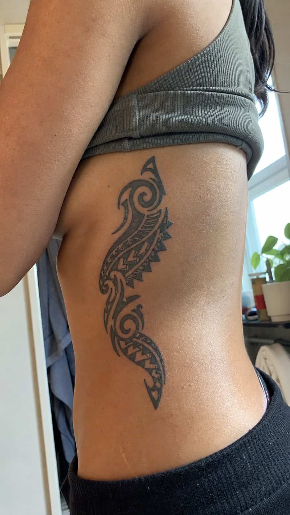 32 Stunning Rib Tattoos for Women 25 Healed tribal designs tattoo on a adult woman's side ribs, photographed in a natural slightly elevated close view — study 2