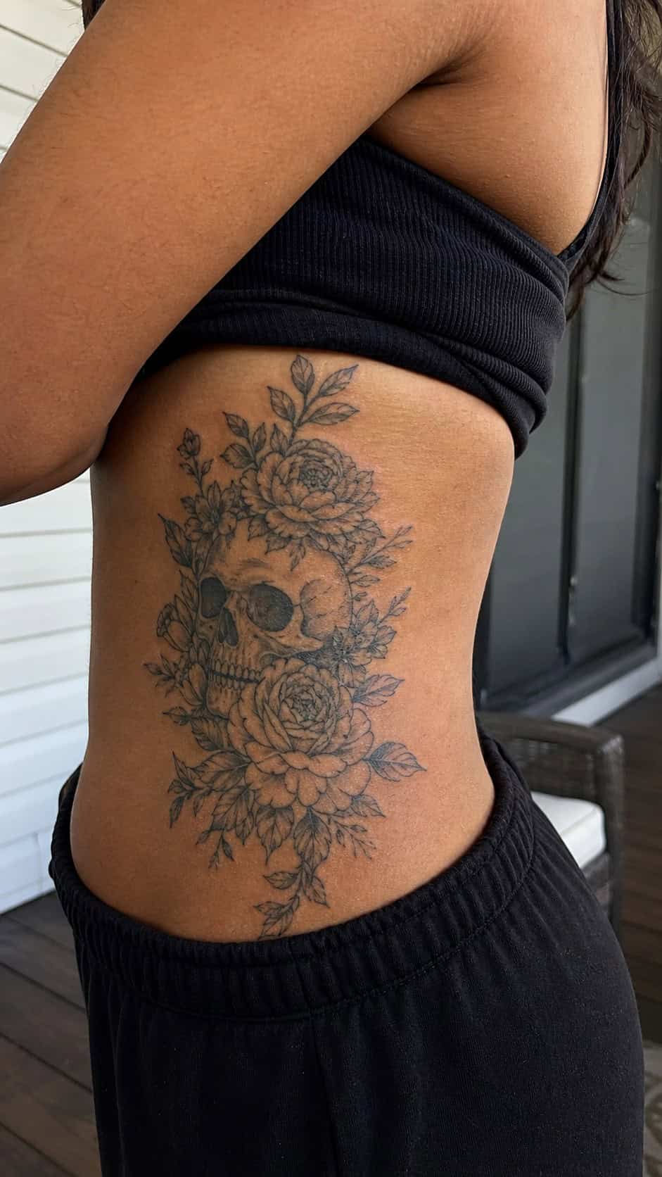 32 Stunning Rib Tattoos for Women 28 Healed floral skull tattoo on a adult woman's side ribs, photographed in a natural straight-on close view, a touch off-center like a — study 1