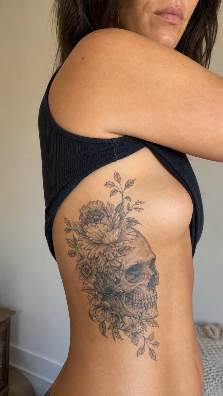 32 Stunning Rib Tattoos for Women 29 Healed floral skull tattoo on a adult woman's side ribs, photographed in a natural gentle side angle that clearly shows how the ink — study 2