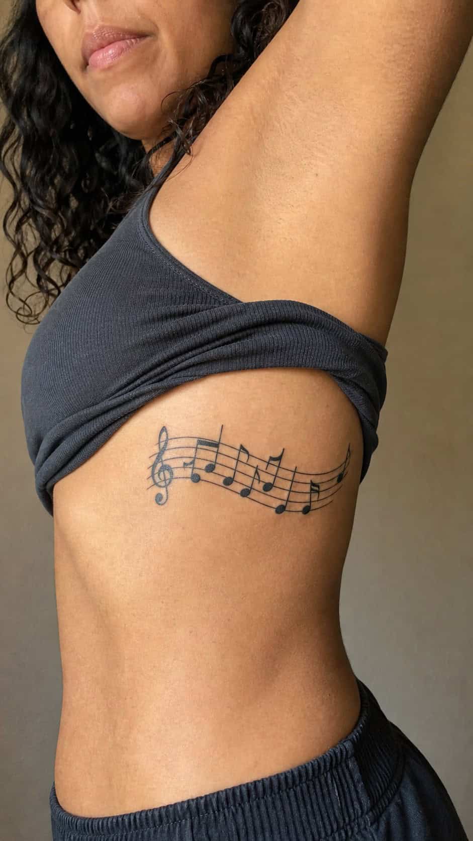 32 Stunning Rib Tattoos for Women 30 Healed musical notes tattoo on a adult woman's side ribs, photographed in a natural casual close three-quarter view — study 1