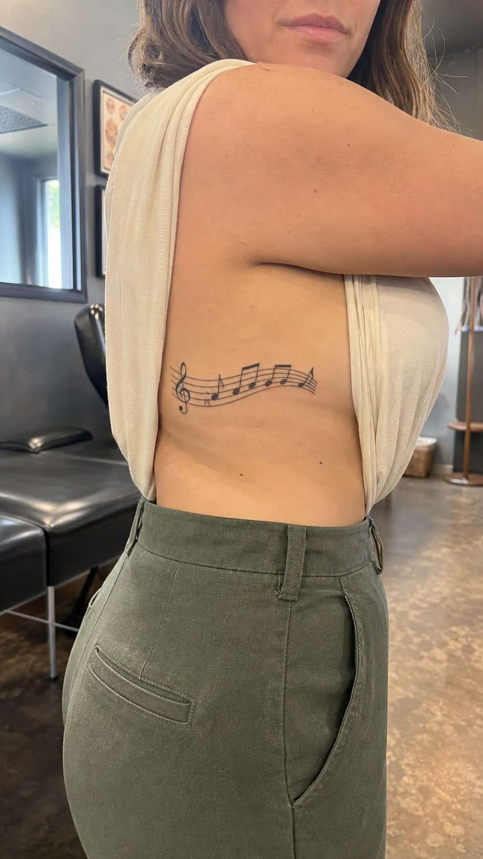 32 Stunning Rib Tattoos for Women 31 Healed musical notes tattoo on a adult woman's side ribs, photographed in a natural straight-on close view, a touch off-center like a — study 2