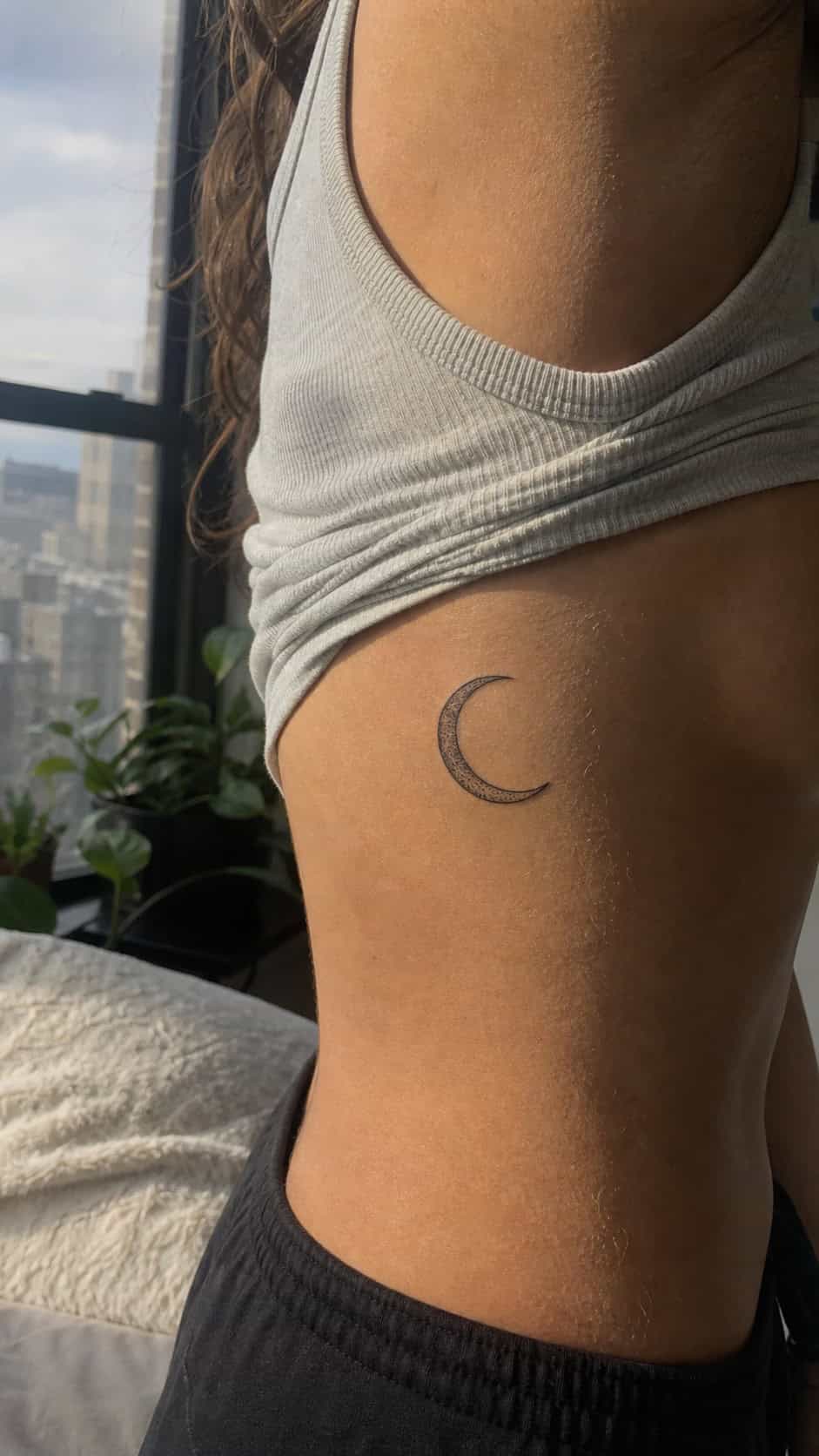 32 Stunning Rib Tattoos for Women 36 Healed crescent moon tattoo on a adult woman's side ribs, photographed in a natural casual close three-quarter view — study 1