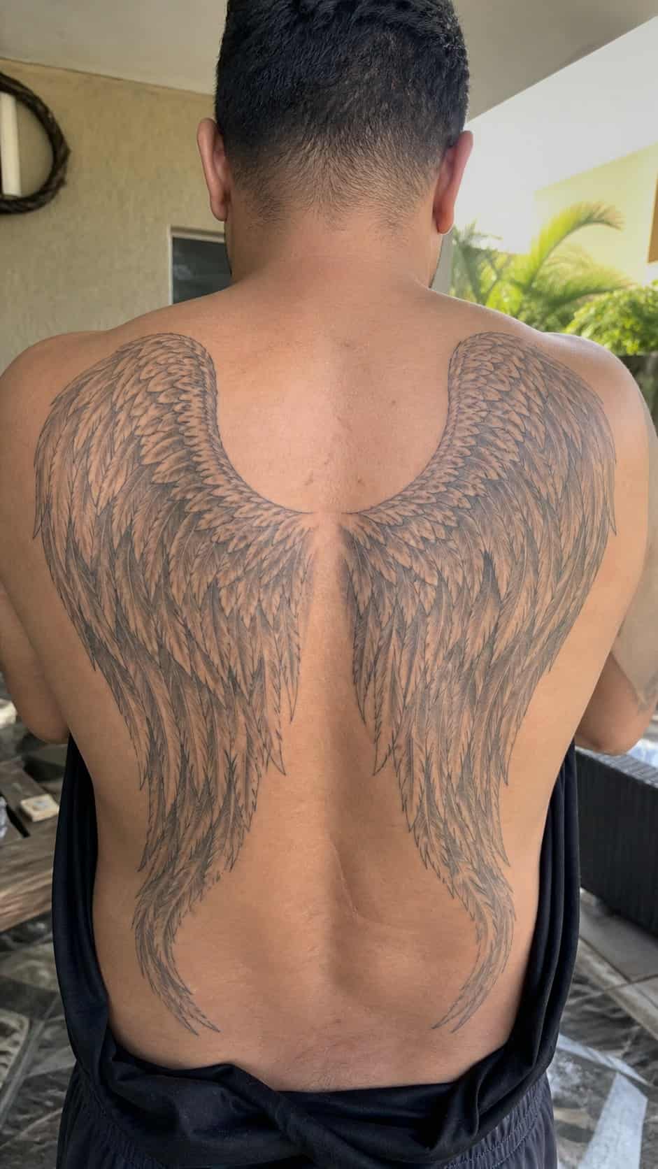 The Art of Ink: 23 Inspirational Back Tattoos for Men 9 Healed angel wings tattoo on a adult man's upper back, photographed in a natural slightly elevated close view — study 1