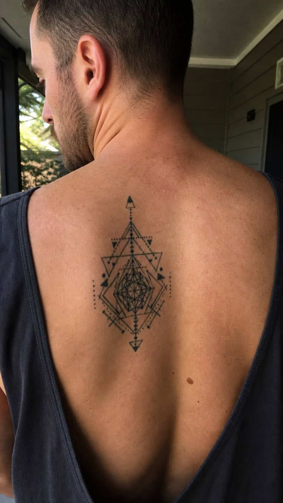 The Art of Ink: 23 Inspirational Back Tattoos for Men 12 Healed geometric patterns tattoo on a adult man's upper back, photographed in a natural casual close three-quarter view — study 1