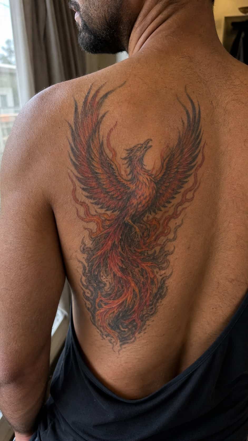The Art of Ink: 23 Inspirational Back Tattoos for Men 14 Healed phoenix rising tattoo on a adult man's upper back, photographed in a natural gentle side angle that clearly shows how the ink — study 1