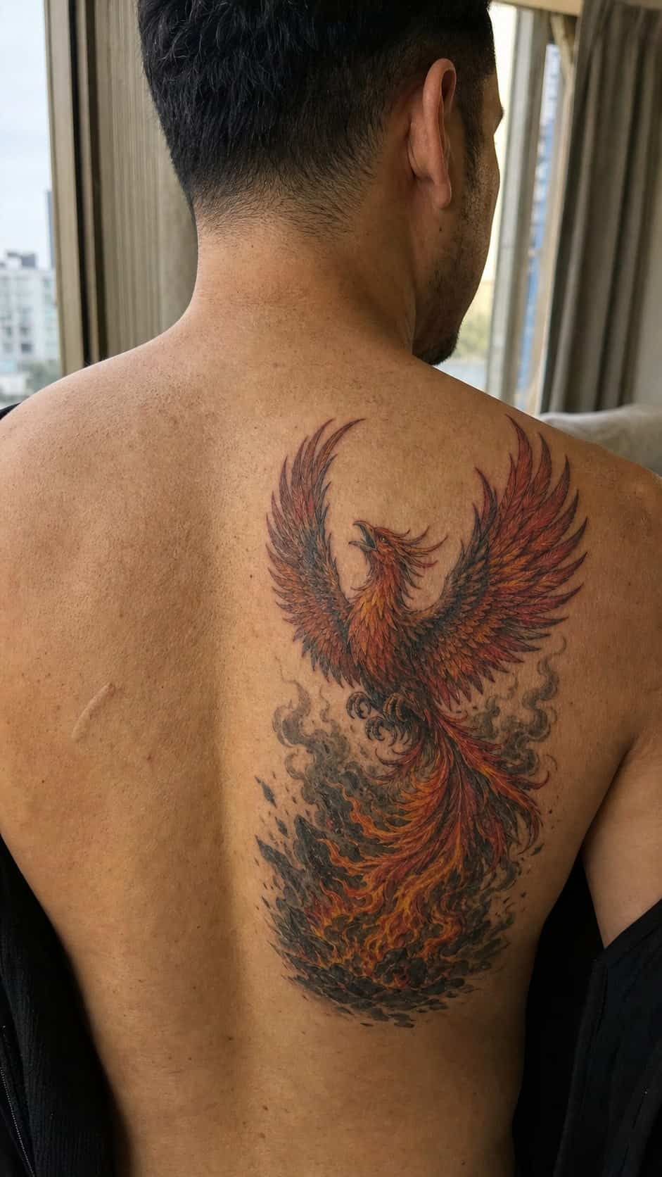 The Art of Ink: 23 Inspirational Back Tattoos for Men 15 Healed phoenix rising tattoo on a adult man's upper back, photographed in a natural slightly elevated close view — study 2