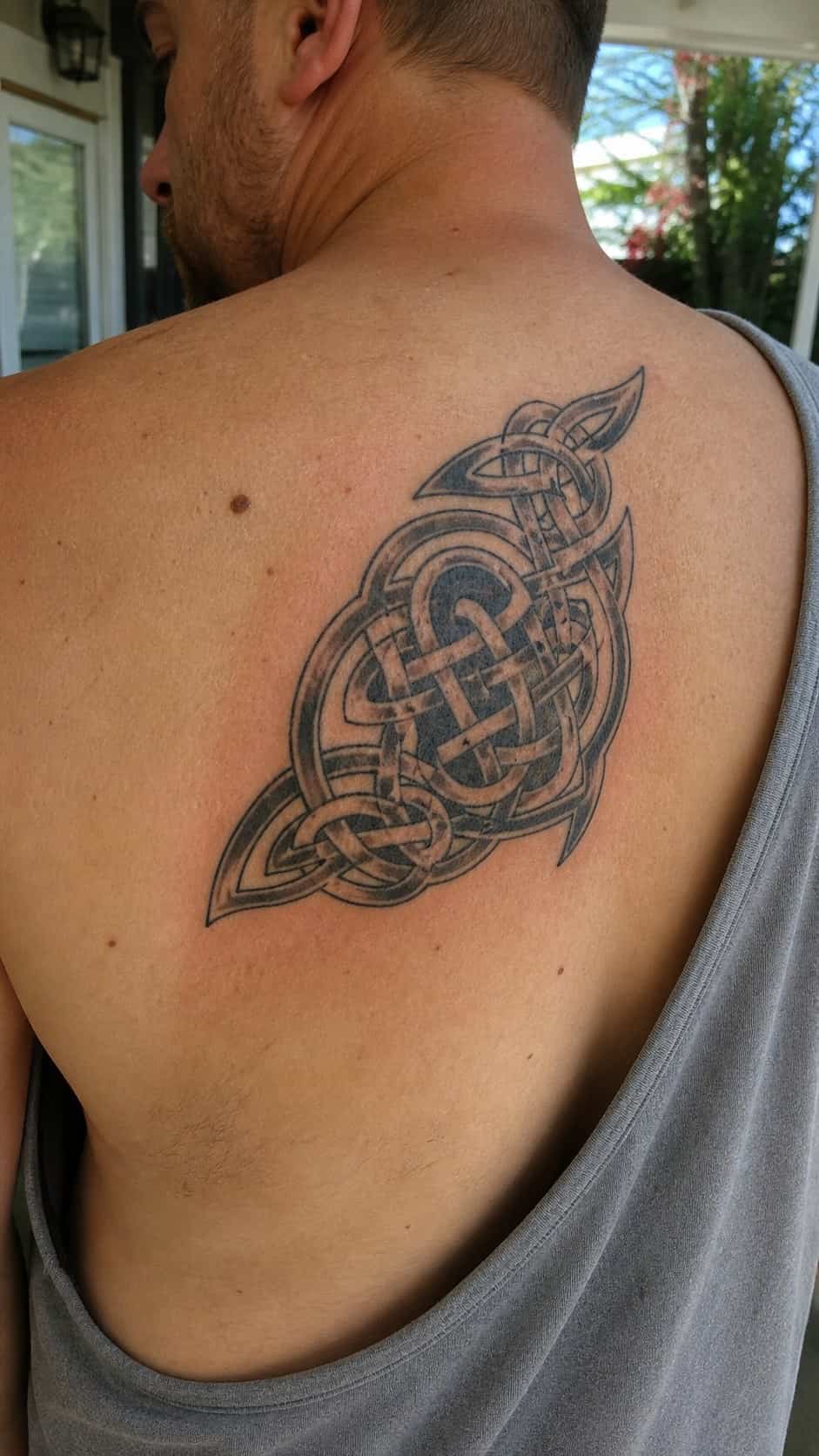 The Art of Ink: 23 Inspirational Back Tattoos for Men 19 Healed celtic knotwork tattoo on a adult man's upper back, photographed in a natural gentle side angle that clearly shows how the ink — study 2