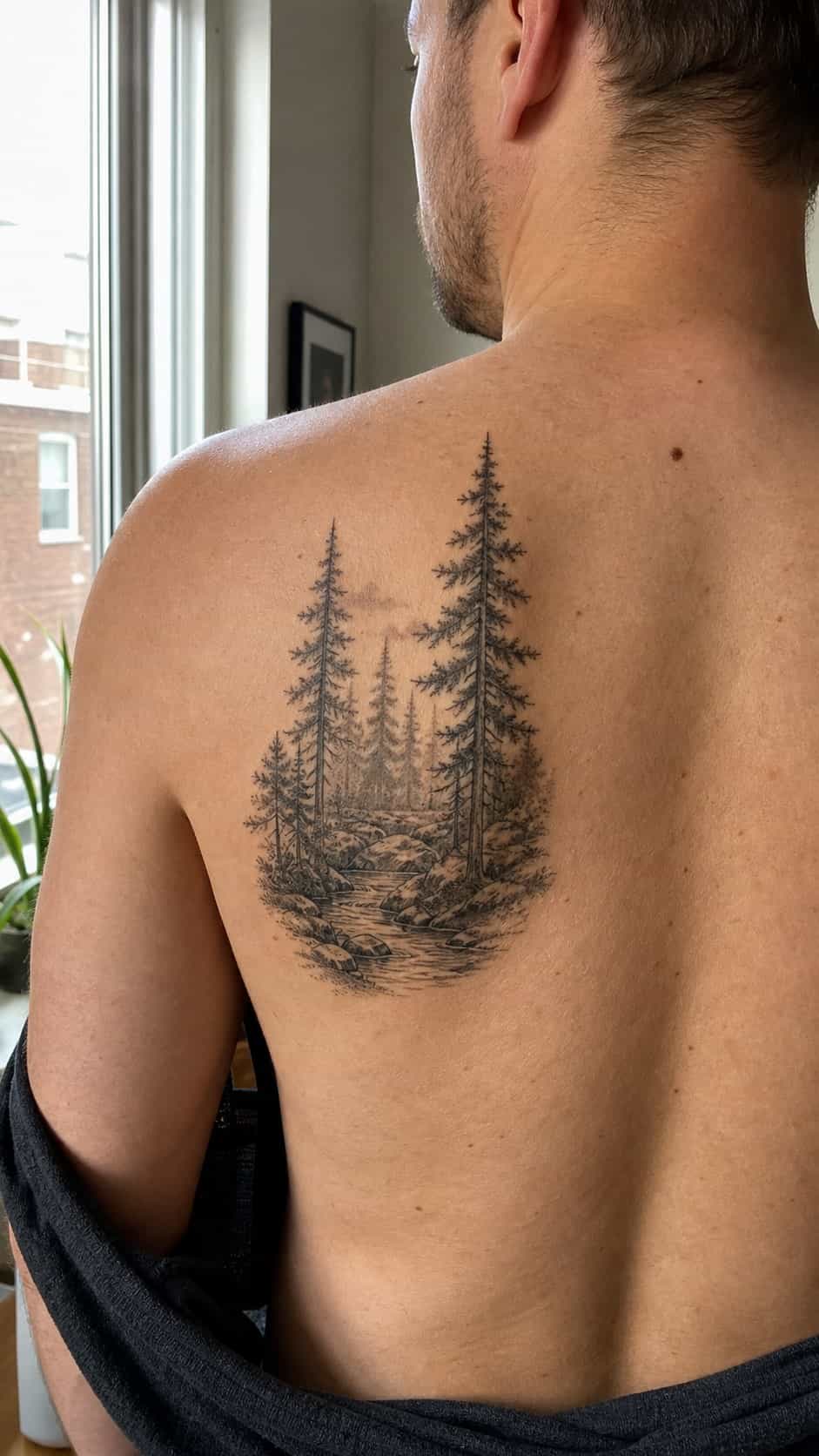 The Art of Ink: 23 Inspirational Back Tattoos for Men 21 Healed forest scene tattoo on a adult man's upper back, photographed in a natural relaxed documentary crop — study 2