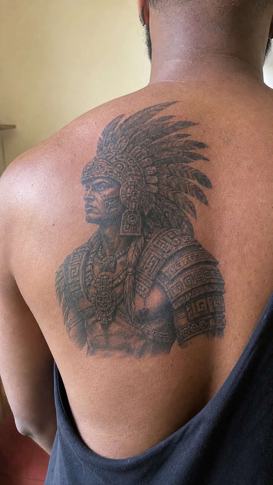 The Art of Ink: 23 Inspirational Back Tattoos for Men 39 Healed aztec warrior tattoo on a adult man's upper back, photographed in a natural straight-on close view, a touch off-center like a — study 2