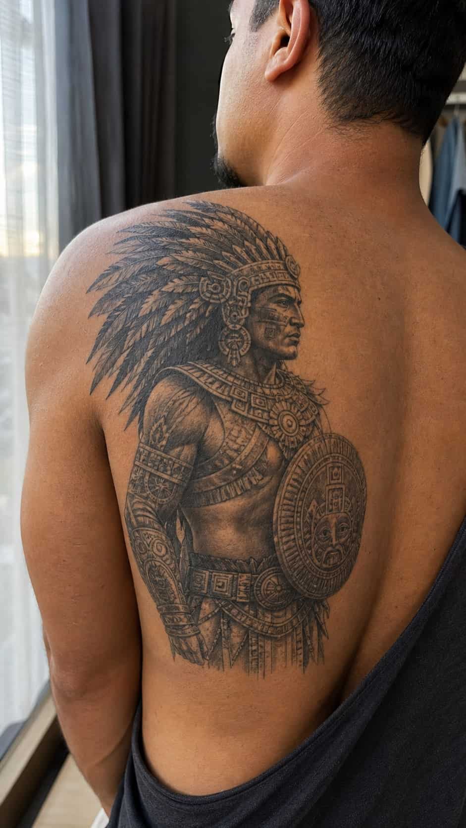 The Art of Ink: 23 Inspirational Back Tattoos for Men 40 Healed aztec warrior tattoo on a adult man's upper back, photographed in a natural gentle side angle that clearly shows how the ink — study 3