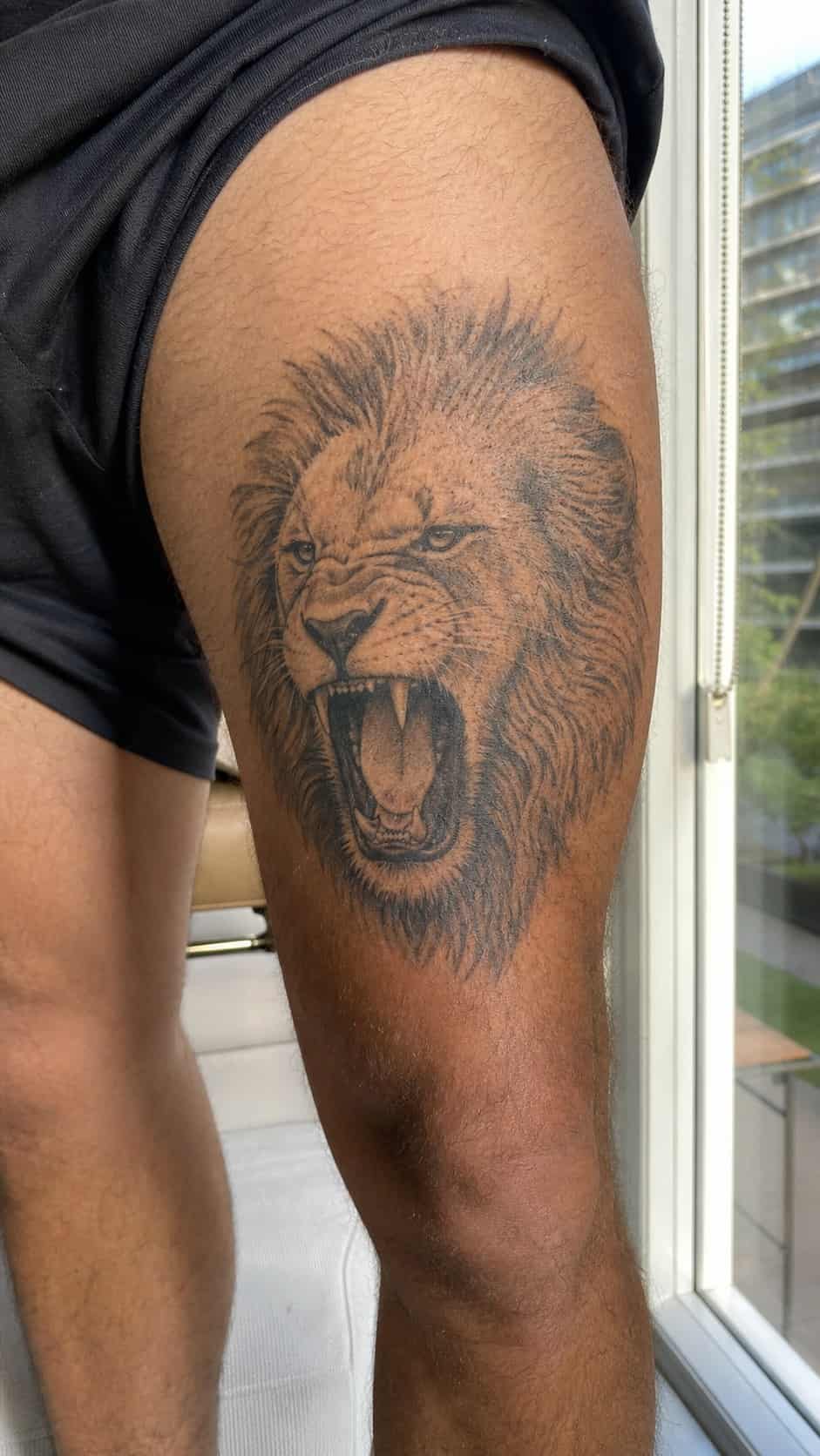 Feeling Bold? Try These 25 Killer Thigh Tattoo Ideas for Men 3 Healed fierce lion roar tattoo on a adult man's outer thigh, photographed in a natural slightly elevated close view — study 2