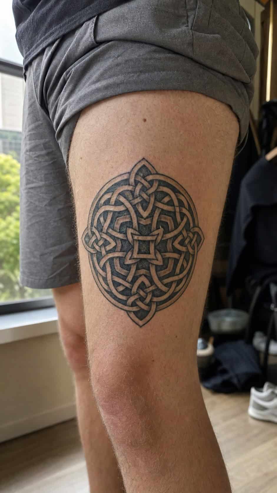 Feeling Bold? Try These 25 Killer Thigh Tattoo Ideas for Men 14 Healed celtic knotwork tattoo on a adult man's outer thigh, photographed in a natural relaxed documentary crop — study 1