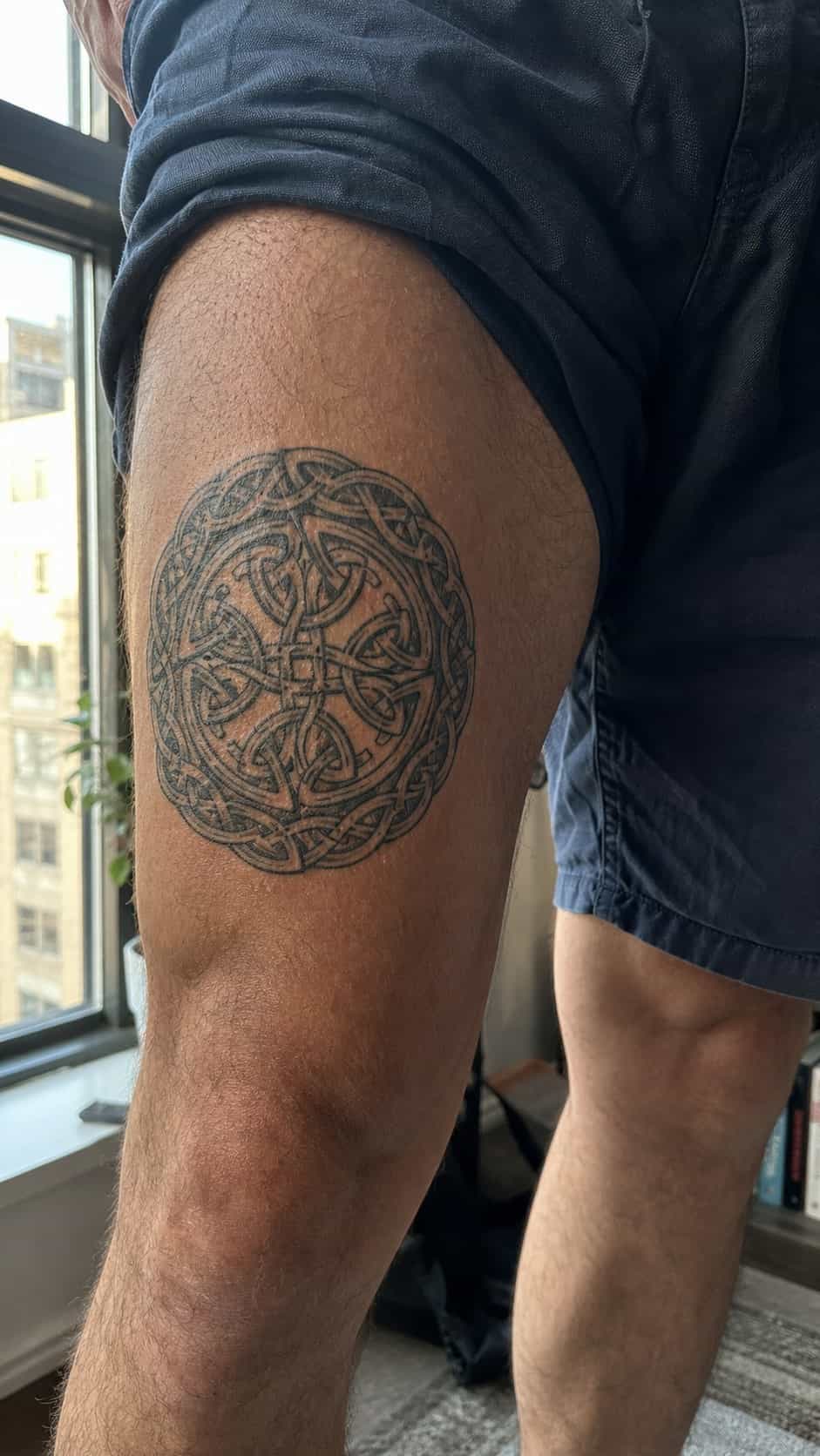 Feeling Bold? Try These 25 Killer Thigh Tattoo Ideas for Men 15 Healed celtic knotwork tattoo on a adult man's outer thigh, photographed in a natural casual close three-quarter view — study 2