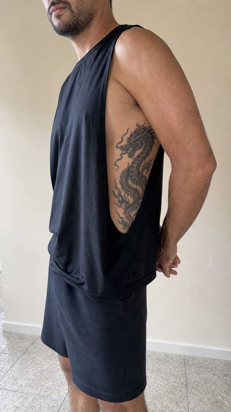 Healed dragon’s fury tattoo on a adult man's side ribs, photographed in a natural casual close three-quarter view — study 1