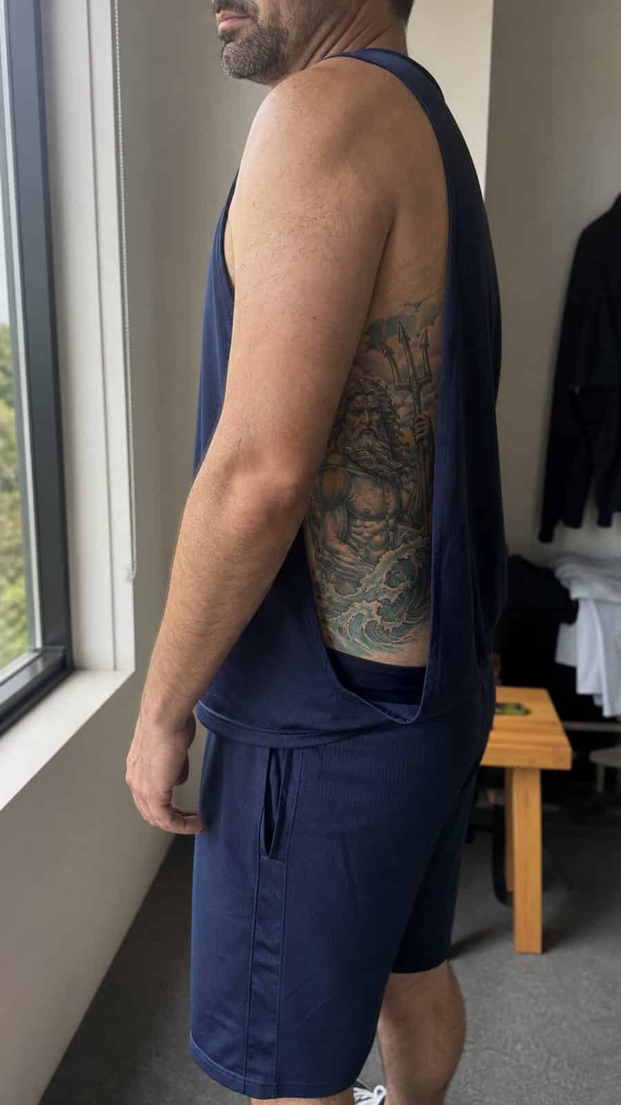 Healed greek god poseidon tattoo on a adult man's side ribs, photographed in a natural waist-height candid close-up — study 1