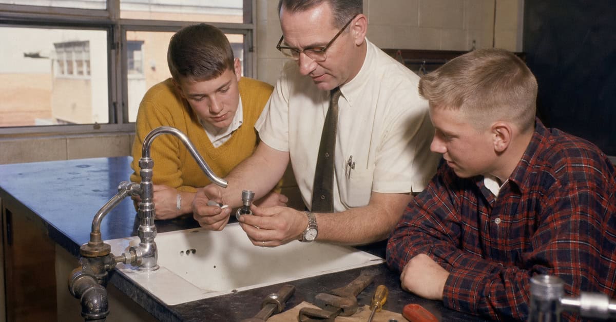 Teacher showing students how to repair a faucet in a 1960s home-maintenance class
