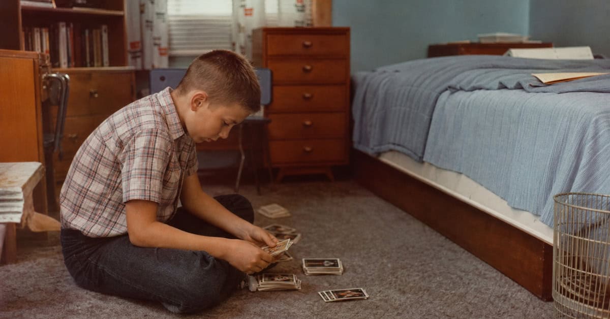 What You Could Actually Buy for Under a Dollar at the Toy Store 11 Child sorting sports trading cards on a bedroom floor in the 1960s