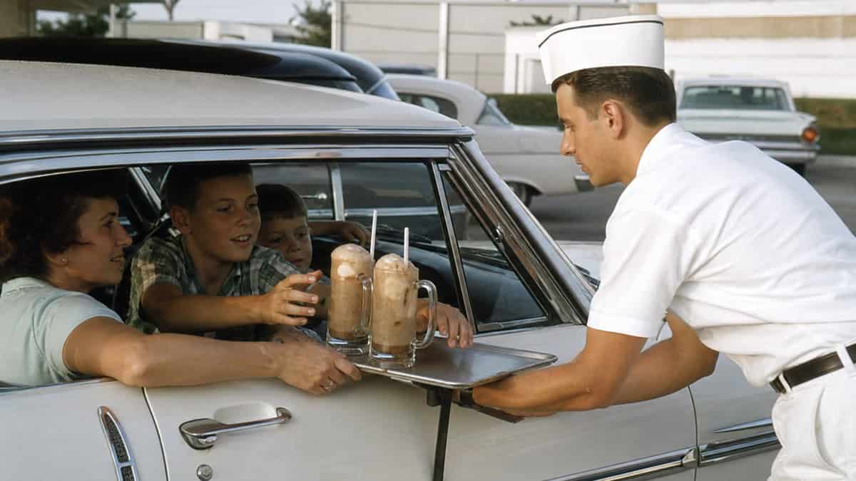 Carhop serving root beer floats at a late-1960s drive-in