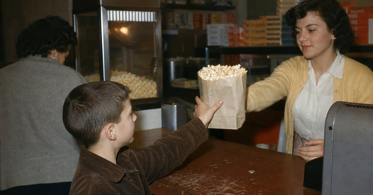 14 Things You Could Buy for a Nickel in 1960 (That Cost $20+ Now) 12 Child receiving a bag of popcorn at a movie theater in 1960