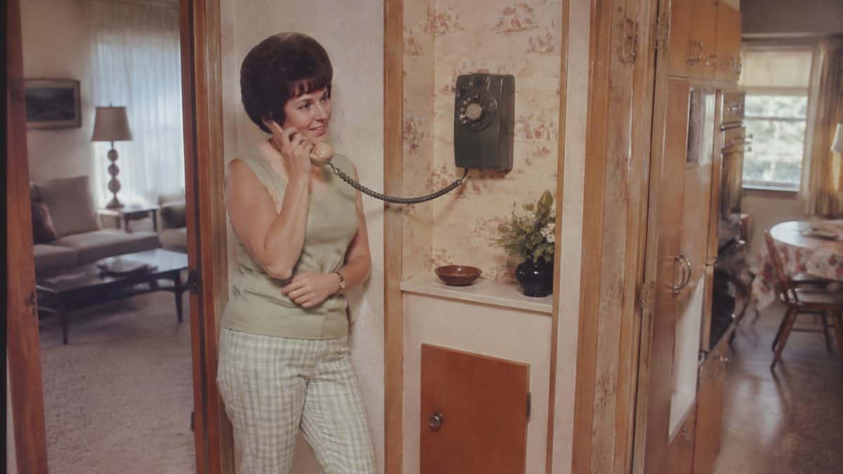 14 Things Every Kid Who Used a Rotary Phone Remembers 8 Genuine mid-century photo of person using wall-mounted phone