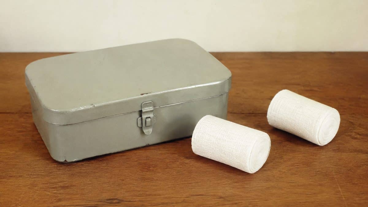 Closed first-aid case and rolled bandages on a 1960s table