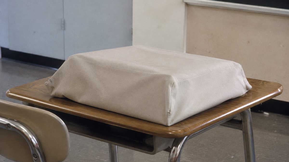 Covered typewriter on an empty 1970s classroom desk