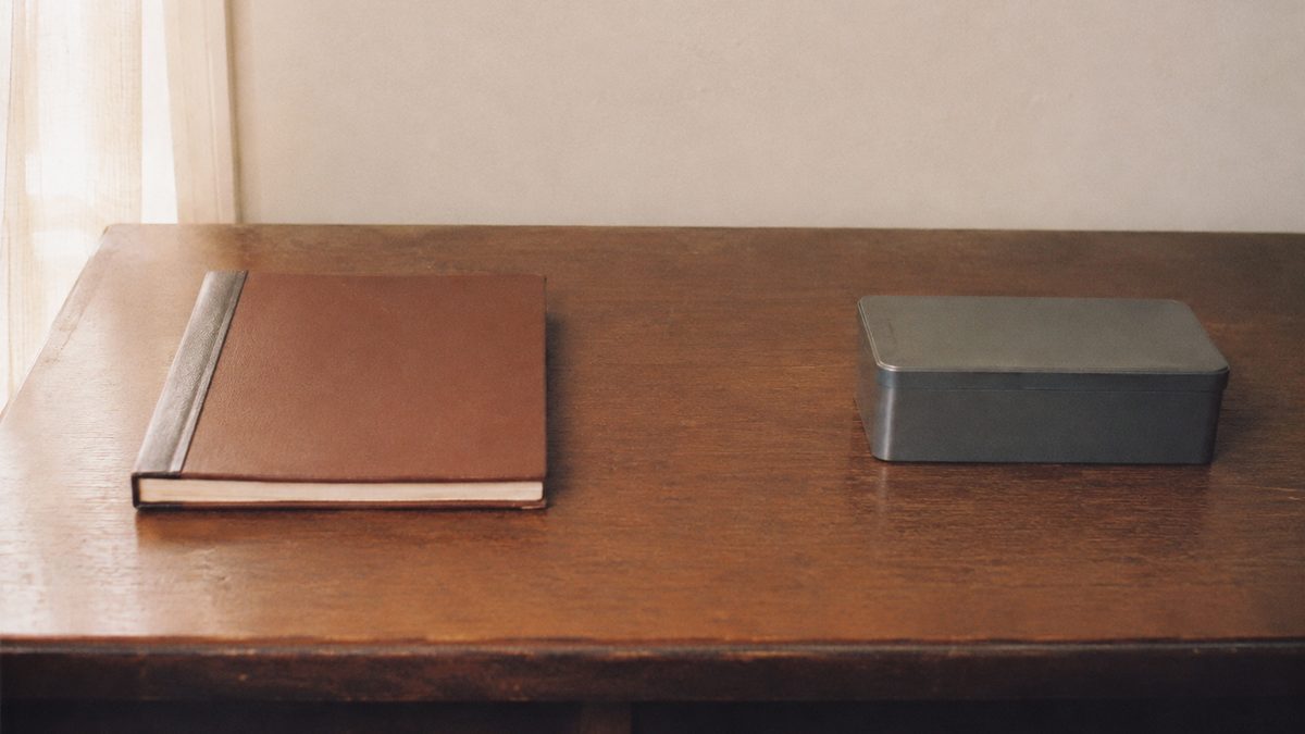 Closed ledger and cash tin on a 1970s home desk