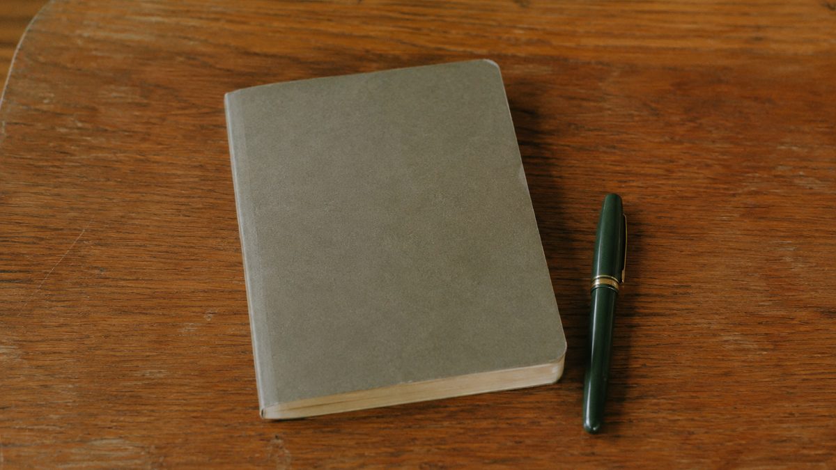 Capped fountain pen beside a closed notebook on a 1960s desk
