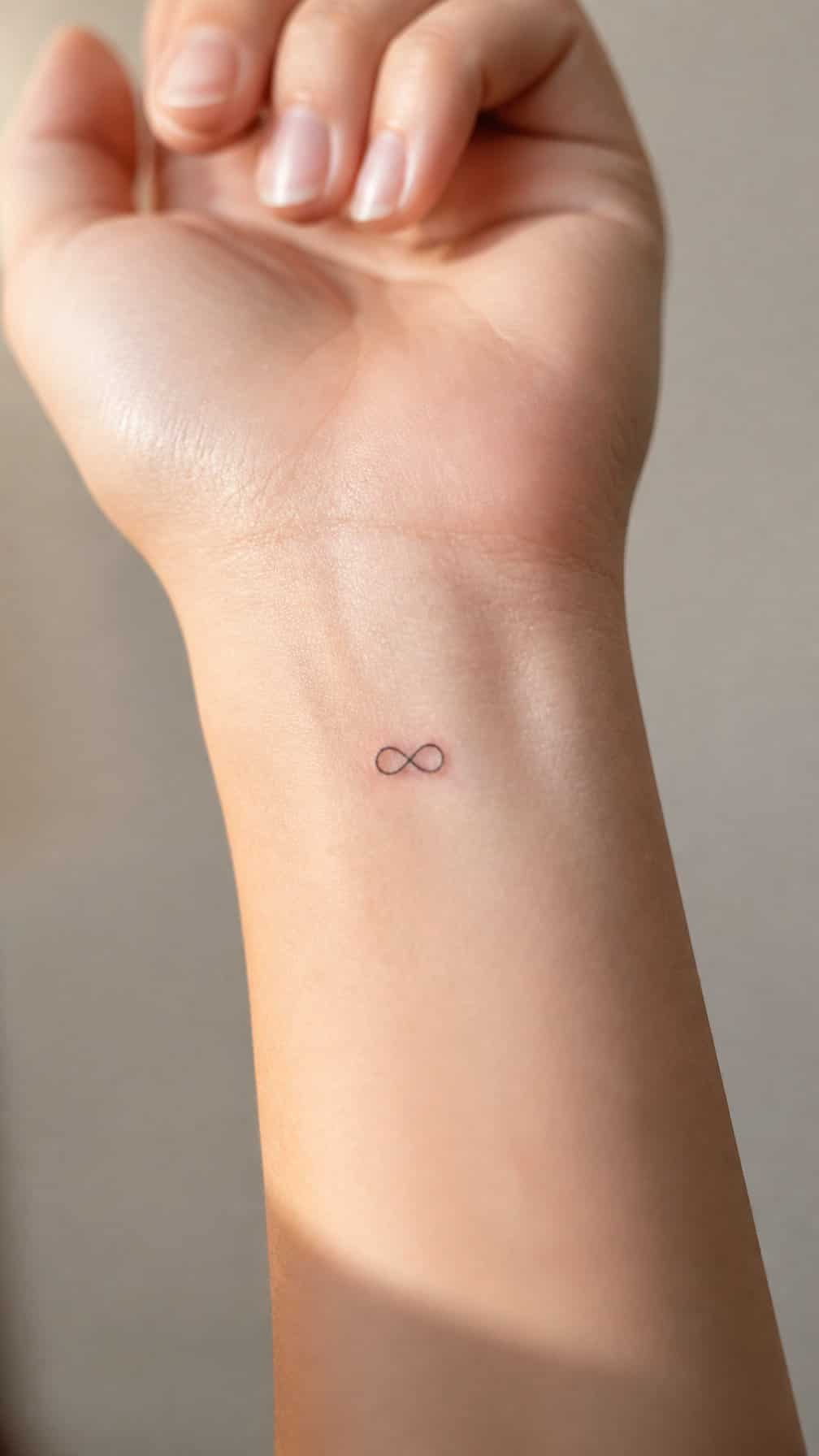 Close-up of a small infinity symbol tattoo on a person’s inner wrist.