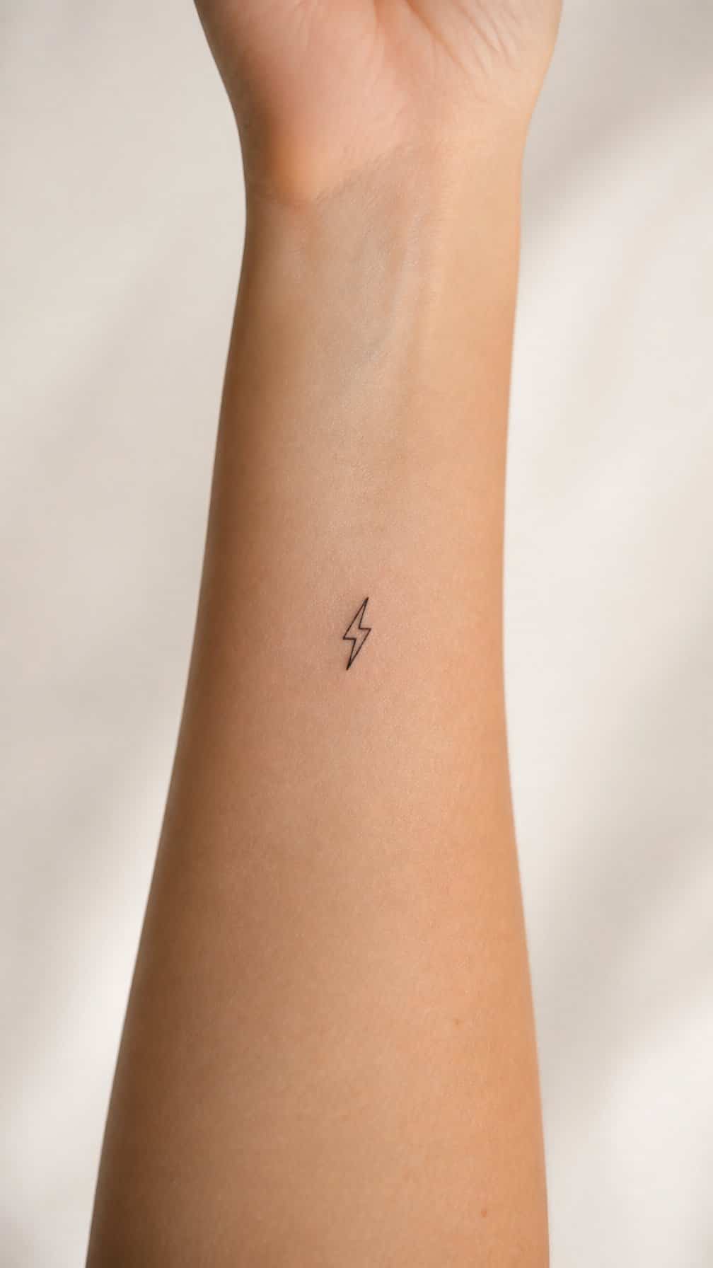 Close-up of an inner forearm with a tiny lightning bolt tattoo.