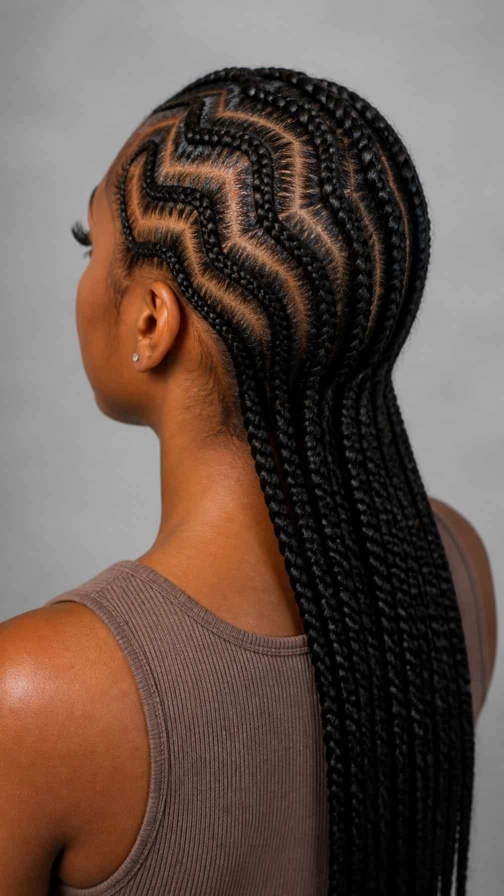 A woman with neatly braided hair poses against a plain light background.