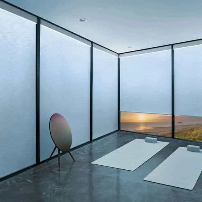 Bright modern yoga space with large windows and ocean sunset view, minimal decor, mats, blocks, and meditation accessories for relaxation and mindfulness.