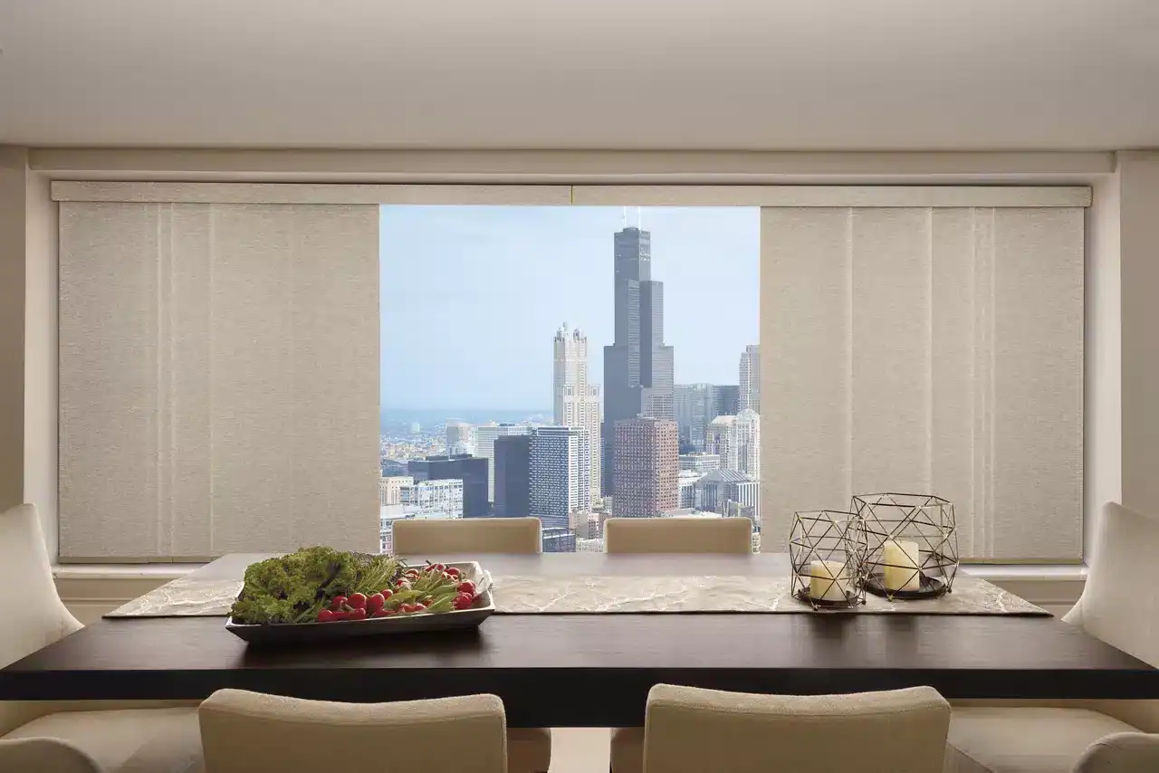 Panoramic view of downtown Chicago from a chic dining room with city buildings and clear daylight through large windows.
