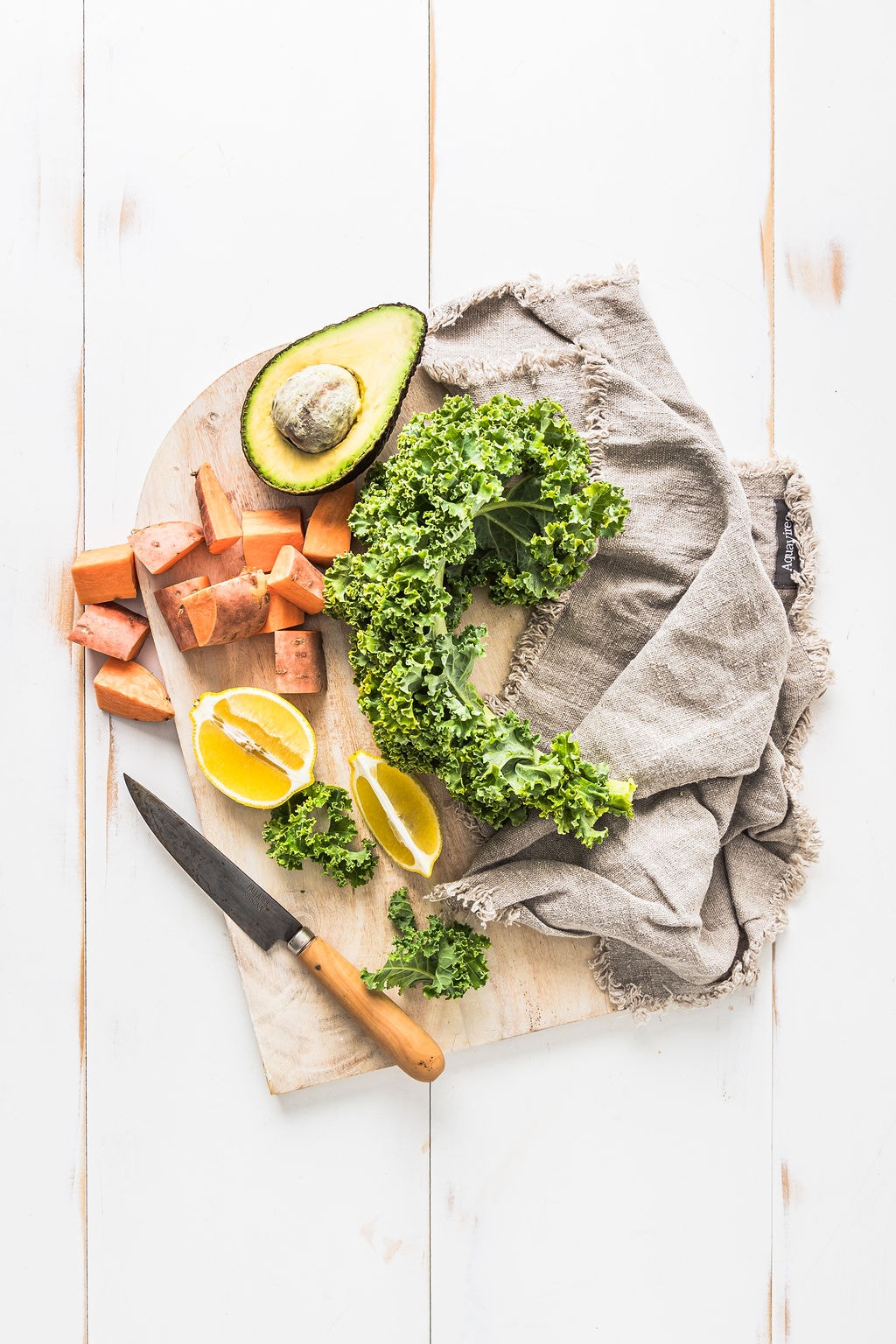 Overhead shot of Sweet potato tofu nourish bowl ingredients, including avocado, kale, lemon and sweet potato.