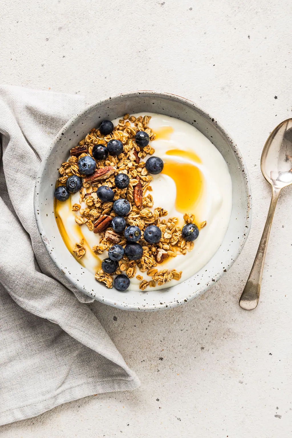 Overhead view of vegan soy yoghurt with granola, honey and blueberries on top.