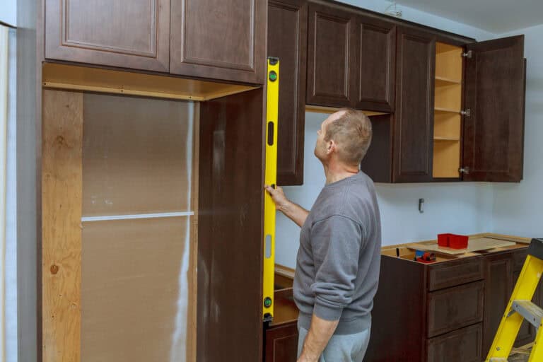 Man using level to check newly installed cabinets