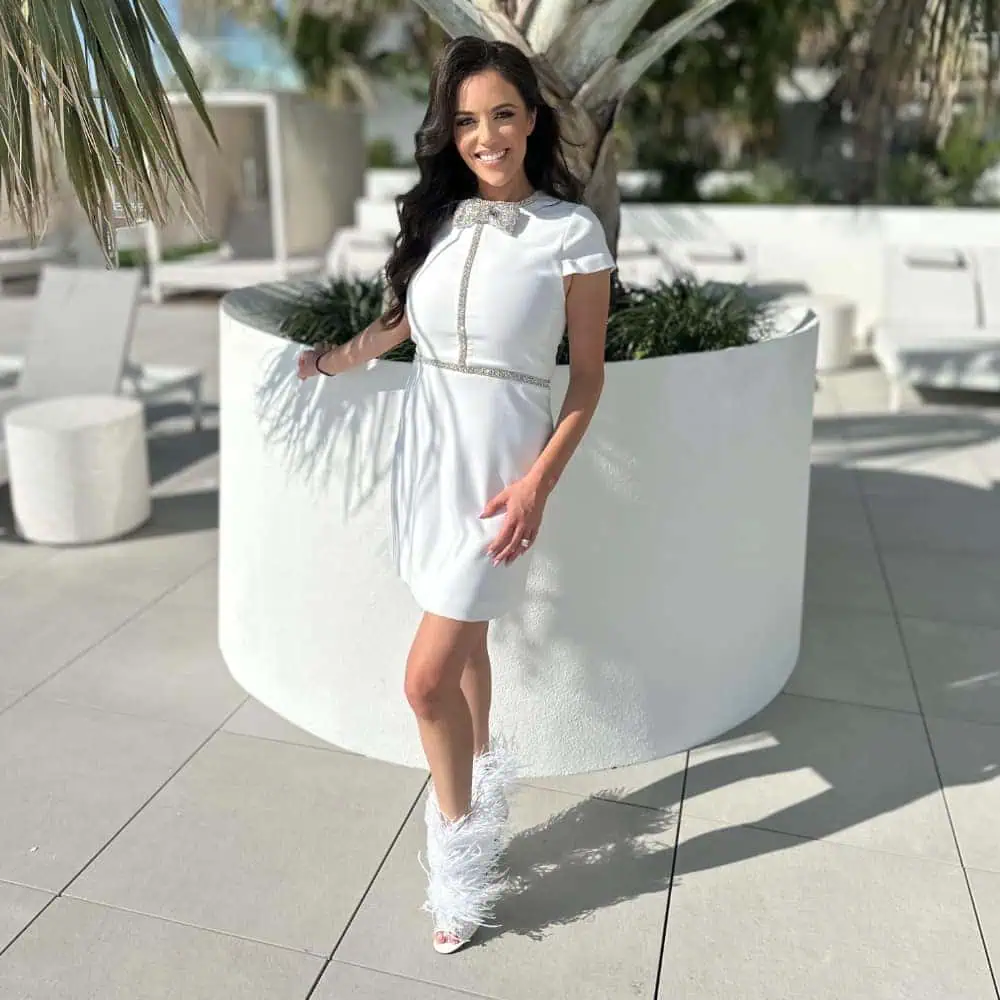 Skylar Porter, SkyStruk CEO wearing white dress and SkyStruk Foxy Open-toe White Stiletto with premium feathers and crystals