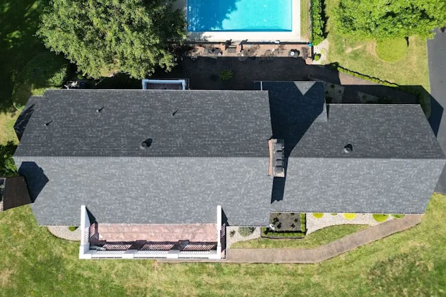 Aerial view of a house with new roofing, backyard pool, and landscaped yard.