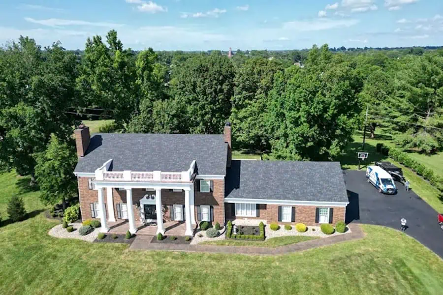 Elegant brick home with a spacious roof and lush green surroundings.