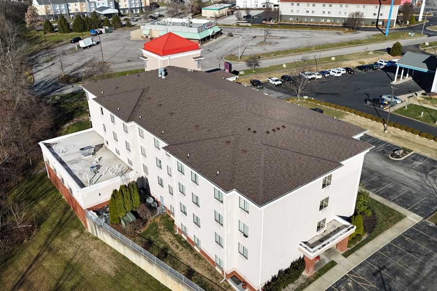 Aerial view of a residential roof with new asphalt shingles in a suburban neighborhood.
