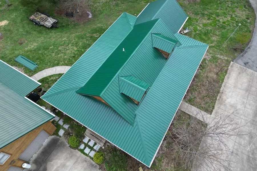 Green metal roof with multiple gables on a residential house.