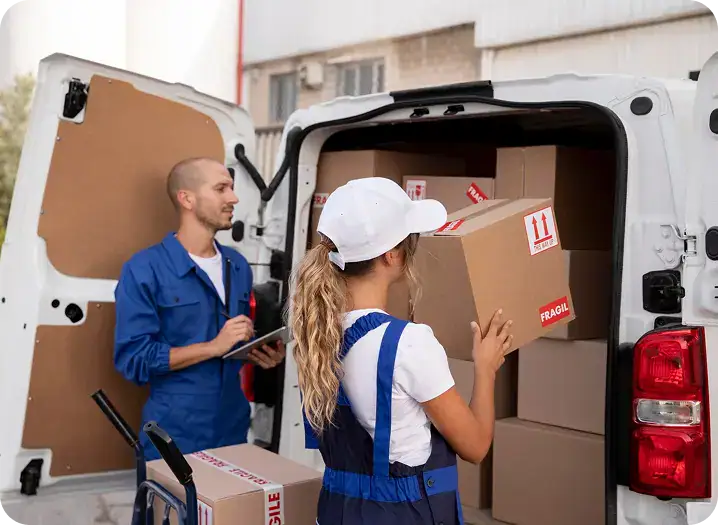 Movers loading boxes labeled "FRAGILE" into a moving van, illustrating efficient packing and customer care in the moving process.