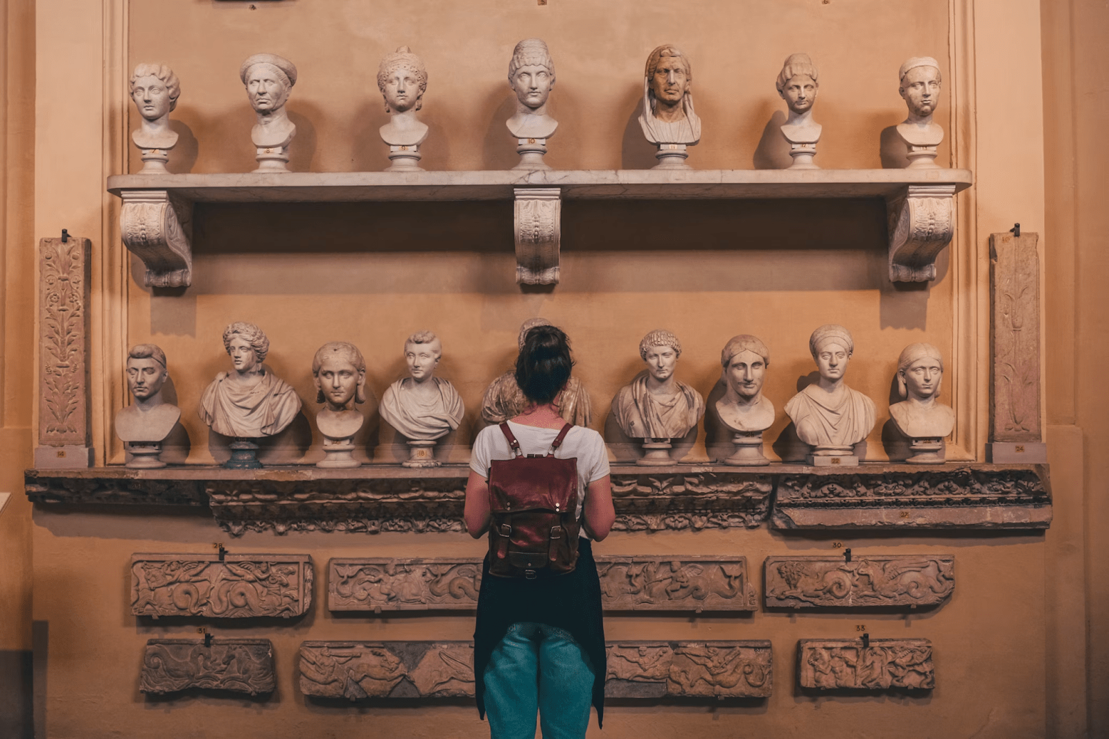 A solo female traveler looking at the display in a museum - (Credits Unsplash)