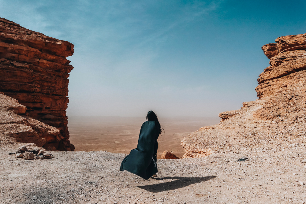 A solo female traveler at a tourist site, exploring the beauty of Saudi Arabia - (Credits About Her)