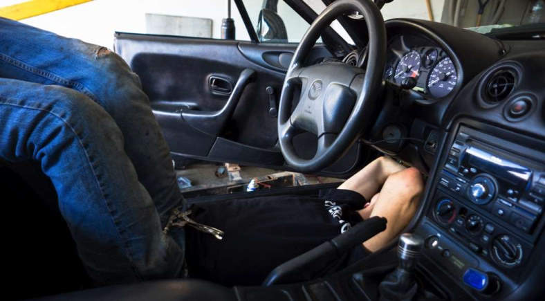 Image of guy looking under Mazda dashboard for LED installation