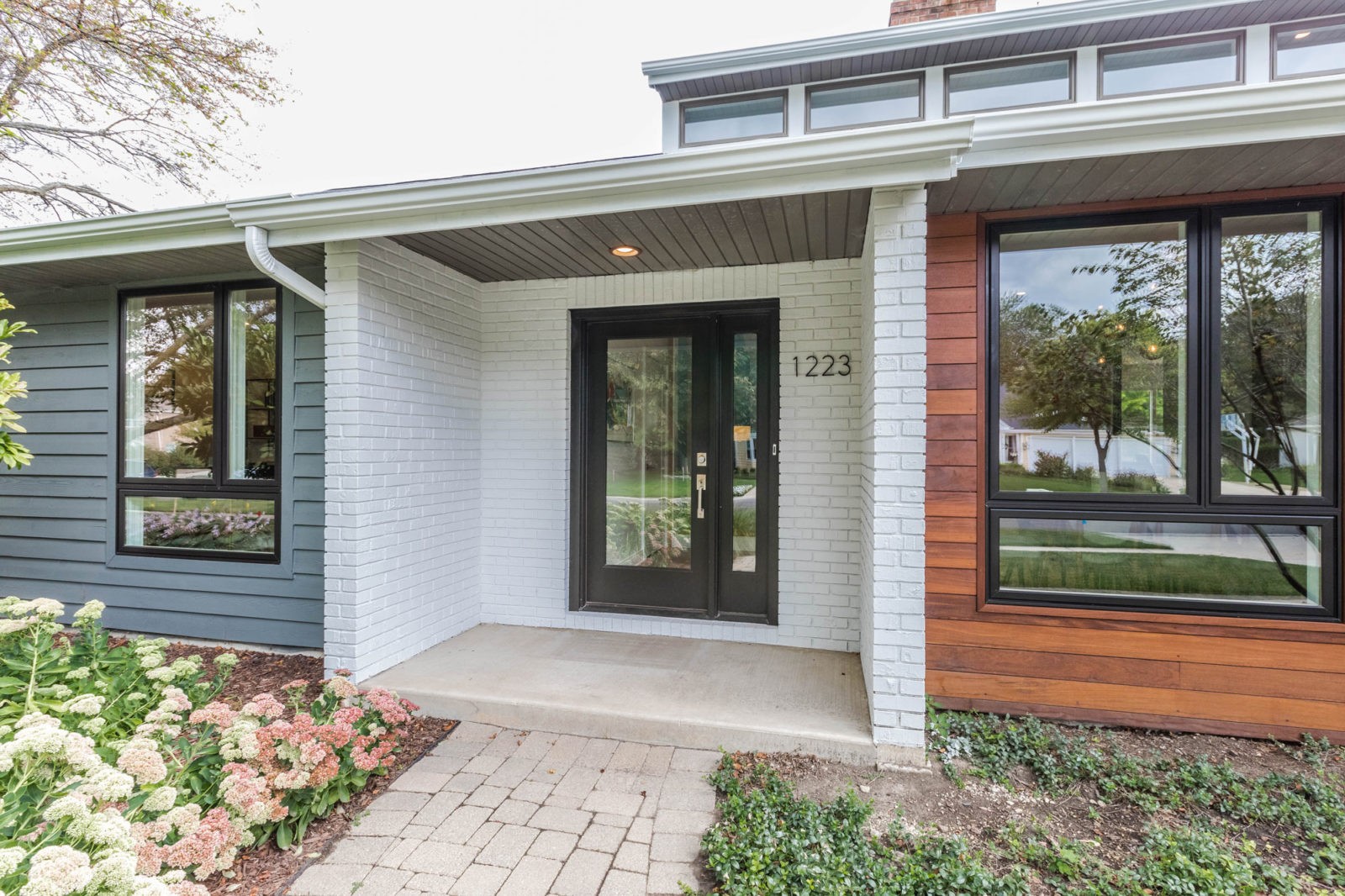 livco exterior home renovation white brick framed porch black glass door framed in black blue siding